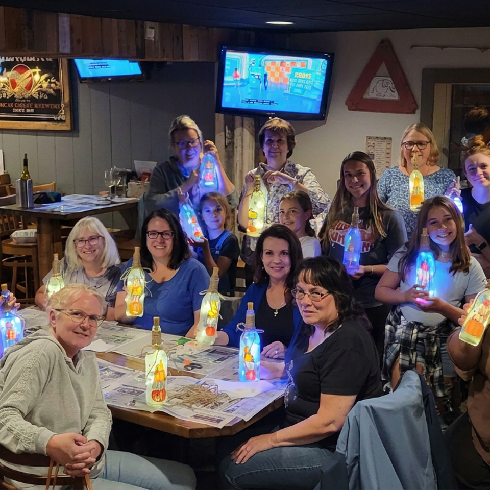 A large group poses inside a cozy restaurant, holding colorful illuminated bottles during a festive gathering.
